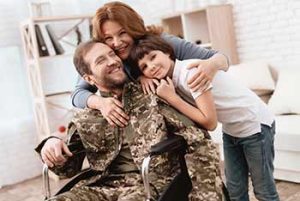 A disabled veteran in wheelchair being hugged by his family because they are now receiving SSDI benefits. 